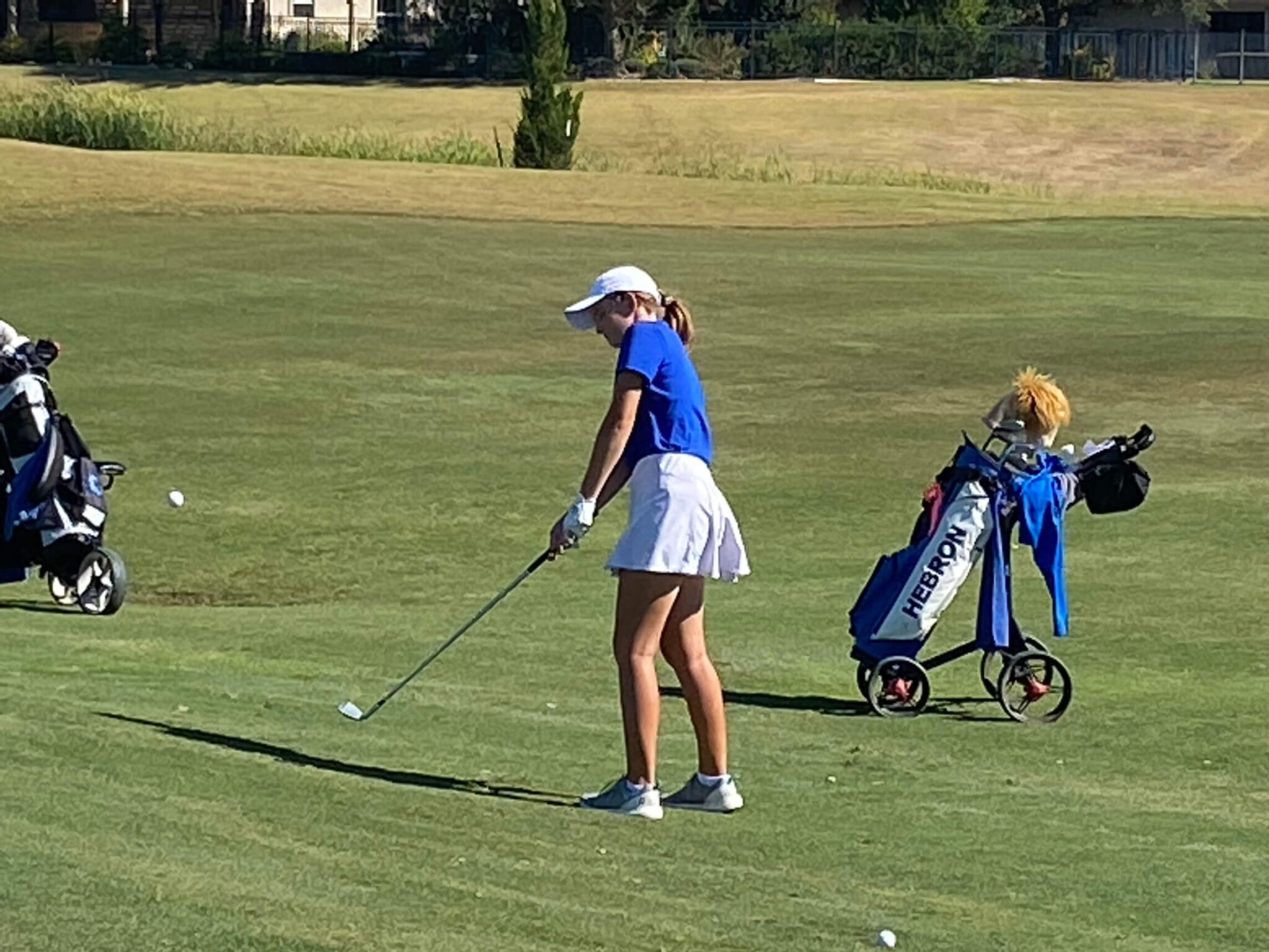 Layla in a Blue Top and White Skirt Playing Golf