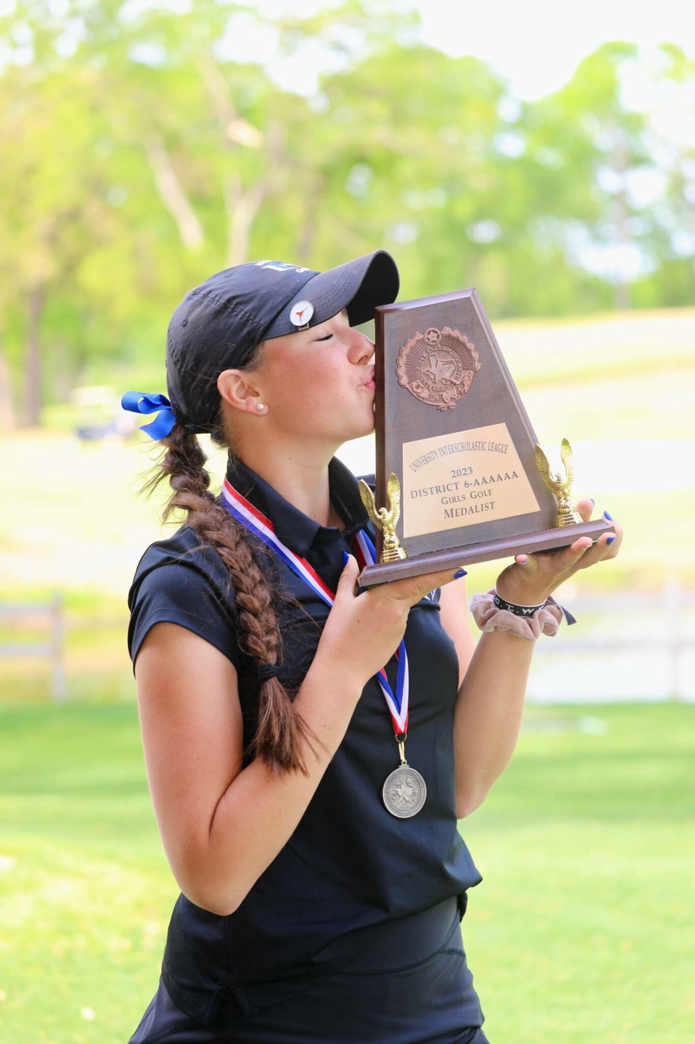 A girl kissing a trophy in an open field